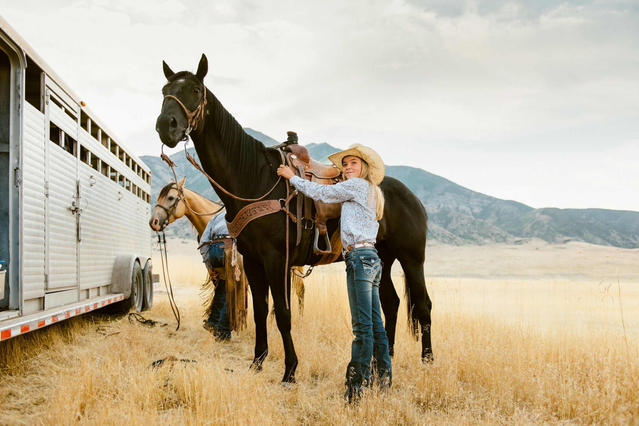 Cowgirl preparing a horse to ride at sunrise